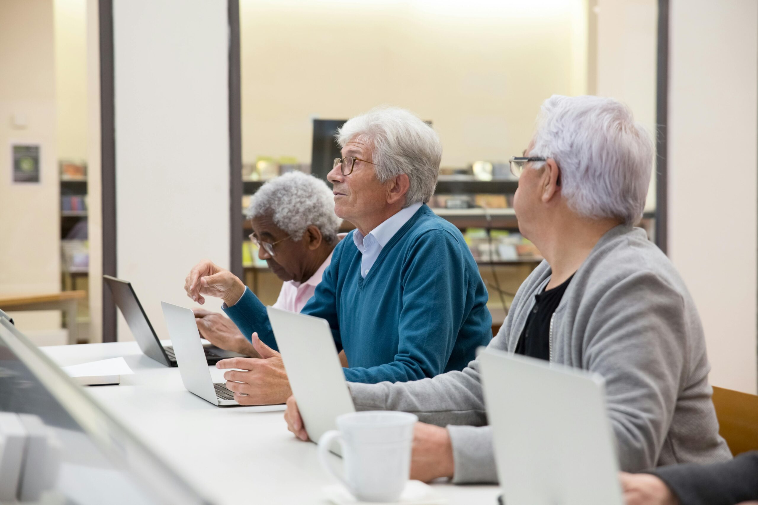 Three elderly persons working on laptops.