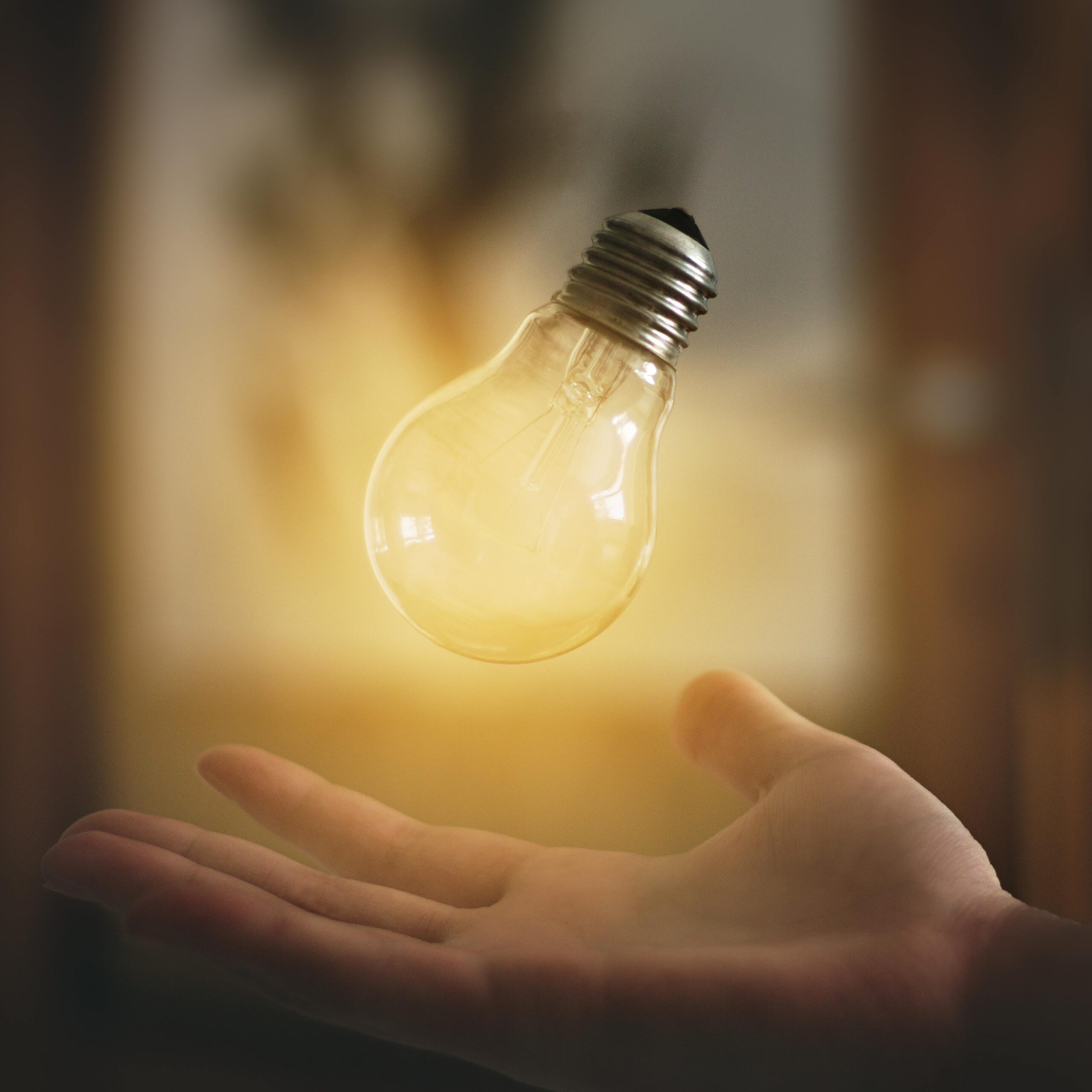 A glowing lightbulb hovering above a hand, representing new ideas. 